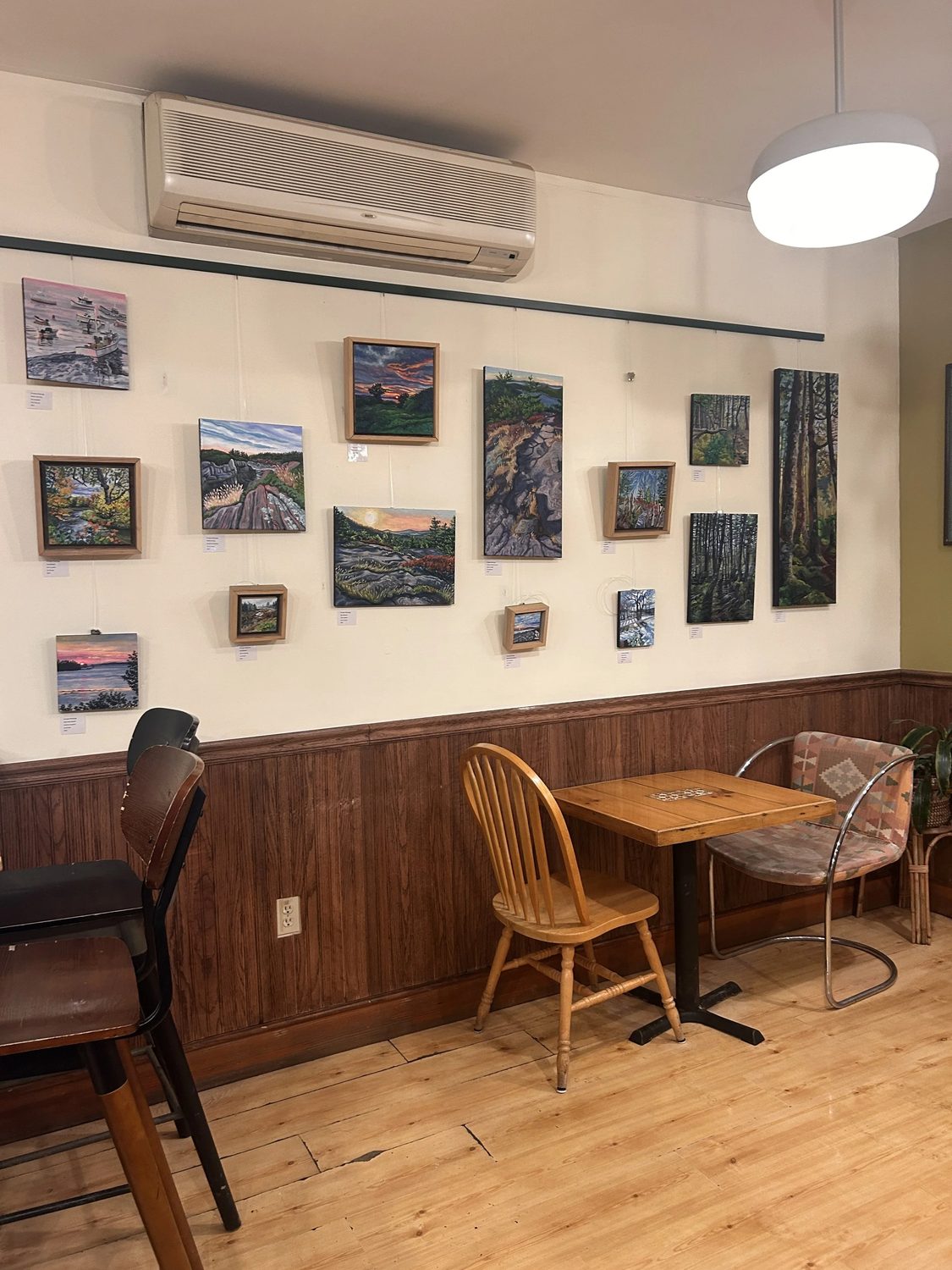 The cafe interior with framed local paintings hung on the wall above a table